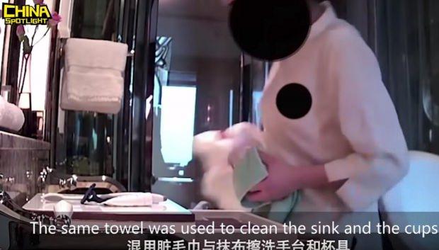 Temizlik görevlisi, havluyla banyoyu temizliyor.