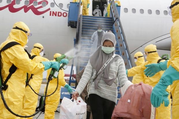 Endonezya'da havalimanında uçaktan inen yolcular dezenfekte ediliyor. 